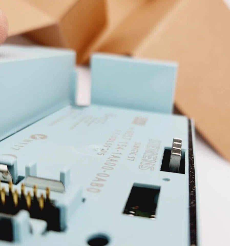 Close-up of Siemens 6ES7154-1AA00-0AB0 SIMATIC DP PROFIBUS Interface-Modul IM154-1 in open packaging, showing ports and details.