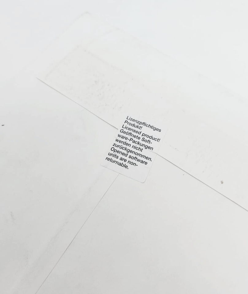 Close-up of a sealed product label in multiple languages, indicating non-returnable and licensed product conditions.