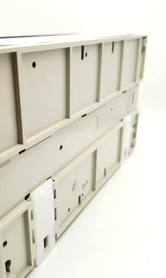 Side view of Mitsubishi FX-64MT-ESS Kompakt-SPS mit Transistorausgängen, featuring mounting points for DIN rail installation.