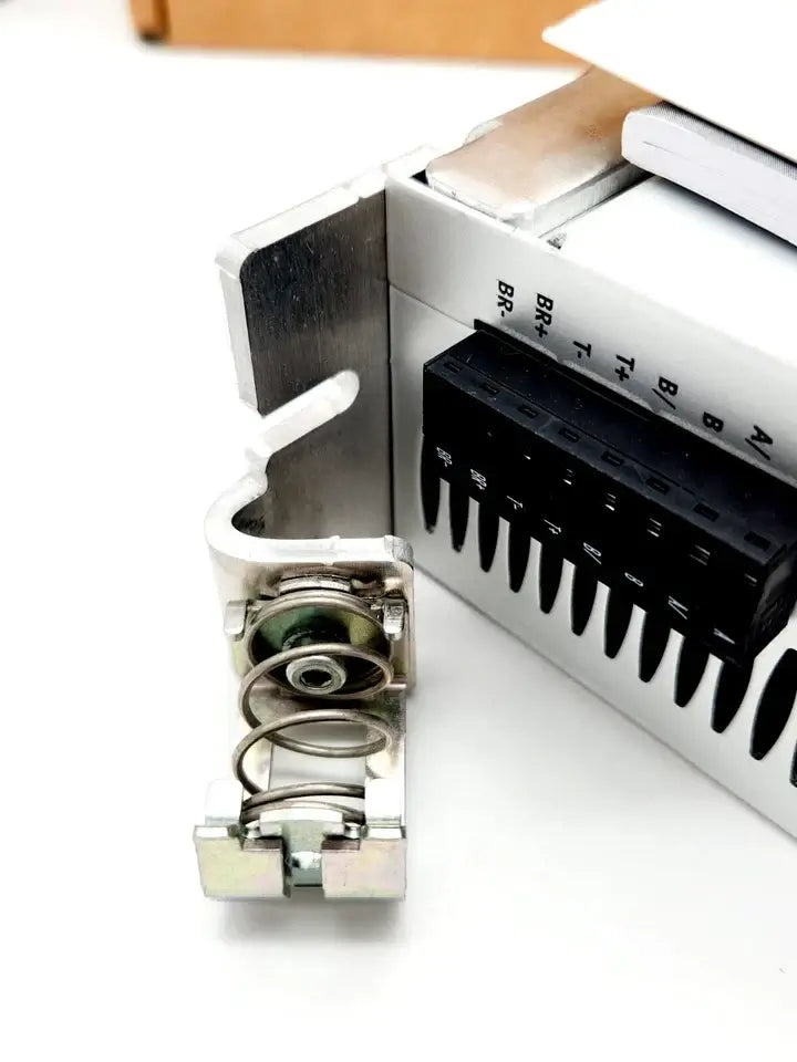 Close-up of a Festo motorcontroller CMMS-ST-C8-7-G2, showing a spring-loaded component and a black connector panel.