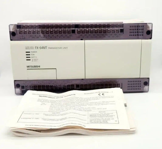 Mitsubishi FX-64MT-ESS compact PLC with transistor outputs, featuring 32 digital inputs and outputs, displayed with manual.